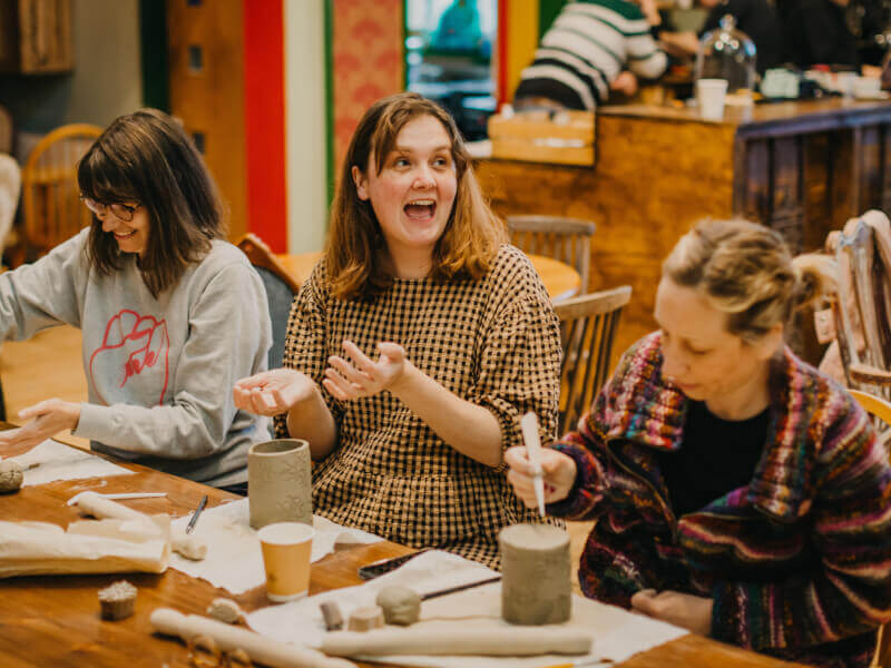 Woman smiling broadly during a pottery workshop